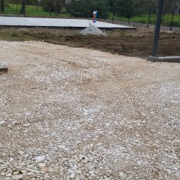 Met-Bud - Przygotowany teren pod budowę z widocznym betonowym fundamentem, stertą piasku i wystającą rurą instalacyjną.