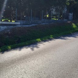 Met-Bud - Wykop pod fundamenty, widoczne zbrojenia i betonowe bloczki na tle drzew i błękitnego nieba.