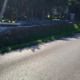 Wykop pod fundamenty, widoczne zbrojenia i betonowe bloczki na tle drzew i błękitnego nieba.