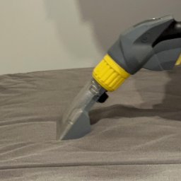 QuickClean - Dysza odkurzacza piorącego z żółtymi elementami czyszcząca szarą tkaninę, widoczne ślady po czyszczeniu.