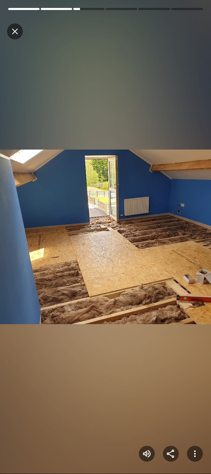 Poddasze z niebieskimi ścianami w trakcie ocieplania: wełna mineralna między legarami i płyty OSB. Widoczny poziomica i pudełko z wkrętami.