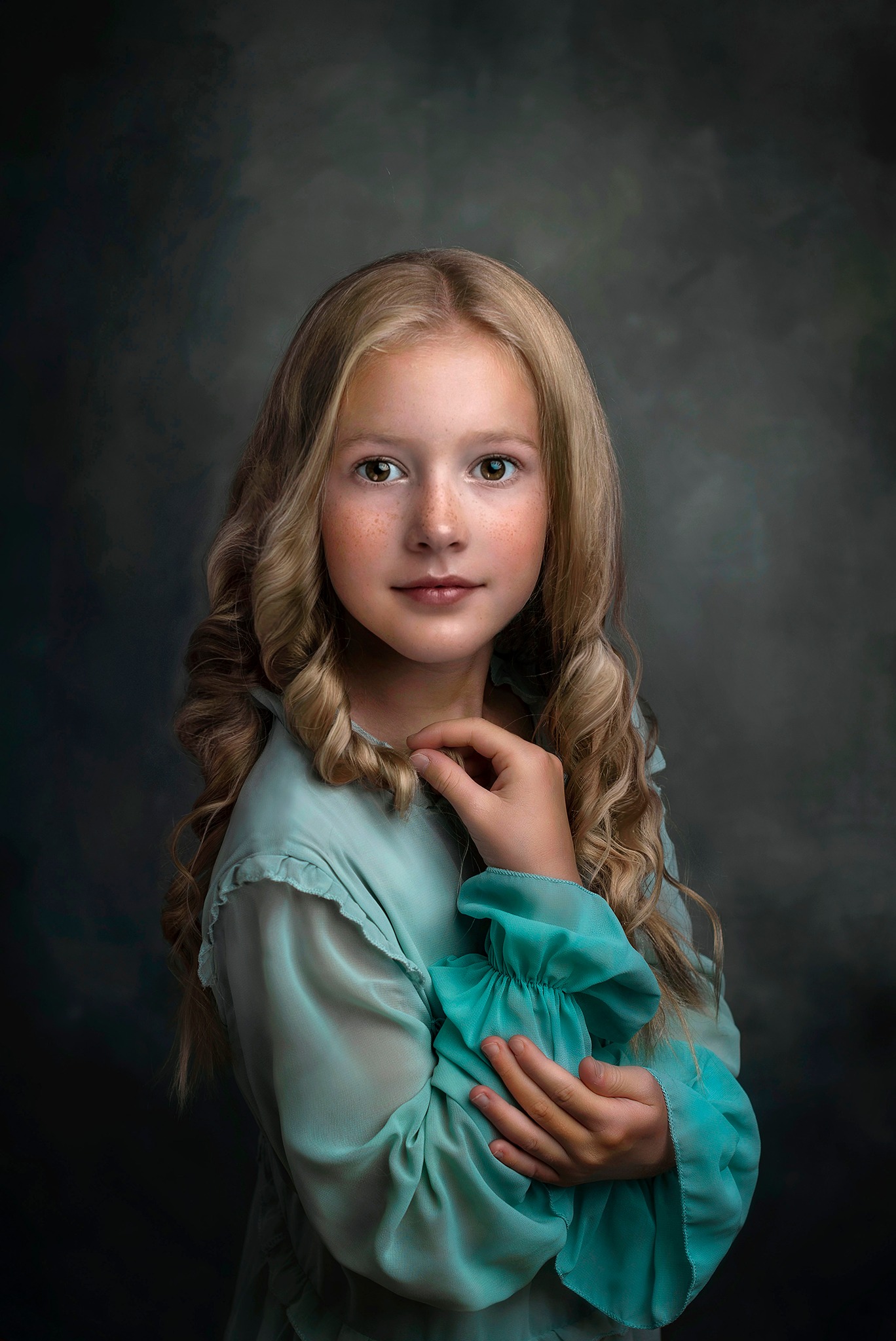 Portret młodej dziewczyny z blond lokami i piegami, ubrana w turkusową sukienkę z bufkami na tle ciemnego, malarskiego tła.