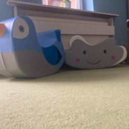 Wyspa Przygód - Pokój dziecięcy z miękkimi zabawkami do siedzenia w kształcie niebieskiego ptaka, szarej chmurki z uśmiechem i brązowego pieska z kością na szyi, ustawionymi na zielonym dywanie.