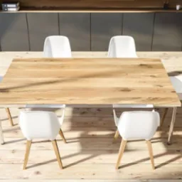 Blat drewniany stołu jadalnego z widocznym usłojeniem, otoczony białymi krzesłami na drewnianej podłodze, z szarą zabudową w tle.