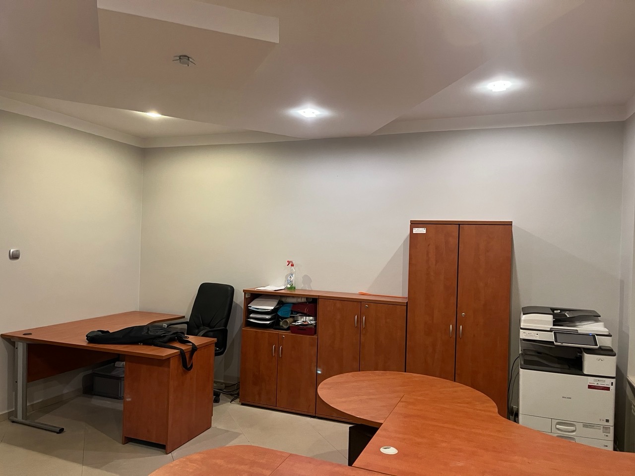 Wnętrze biura po malowaniu ścian w Gliwicach. Widoczny stół, krzesło, szafki i sprzęt biurowy. Ściany w odcieniach bieli, oświetlenie sufitowe.