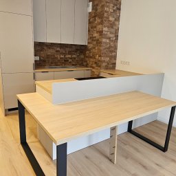 HOLZF - Nowoczesna kuchnia z wyspą i ceglaną ścianą, jasne fronty szafek i blat z drewnopodobnym dekorem, czarne nogi wyspy.