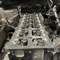 MB Rescue&Care - Głowica silnika Mercedes-Benz po obróbce, z widocznymi zaworami, sprężynami i śrubami, zamontowana w komorze silnika, z numerem identyfikacyjnym 03 R 656 016.