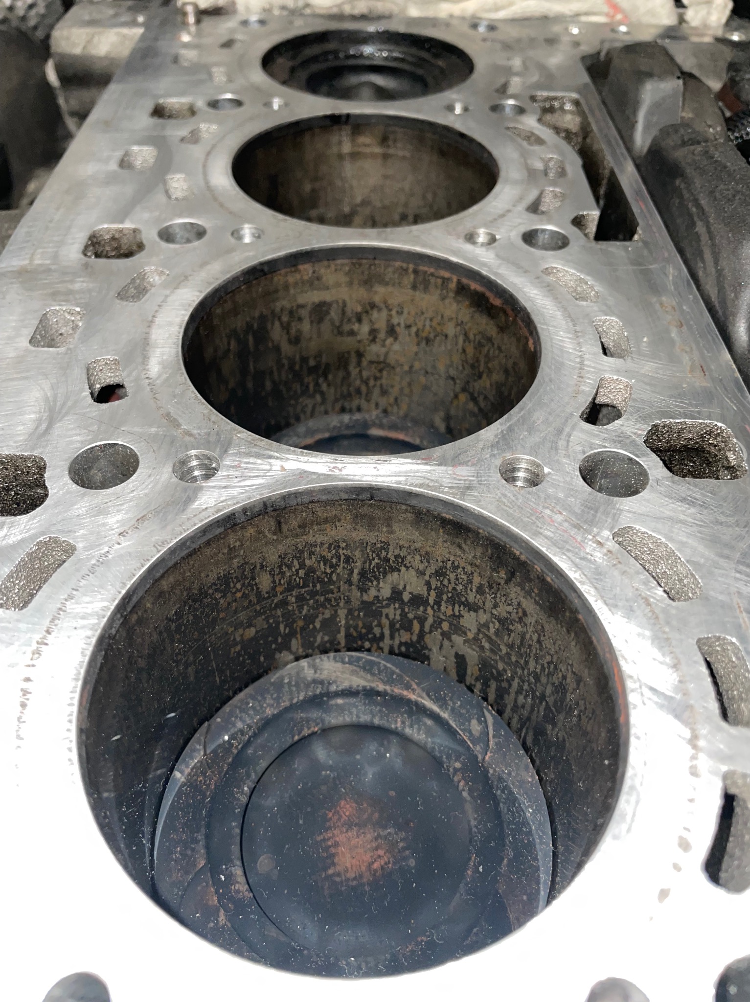 Blok silnika z widocznymi cylindrami i tłokiem, ślady zużycia widoczne na powierzchniach.