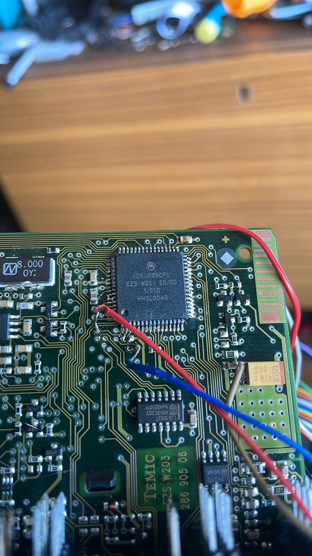 Zbliżenie na płytkę drukowaną z układem scalonym Xc511029cfu, widoczne przewody lutowane do pinów układu, elementy elektroniczne i ścieżki.