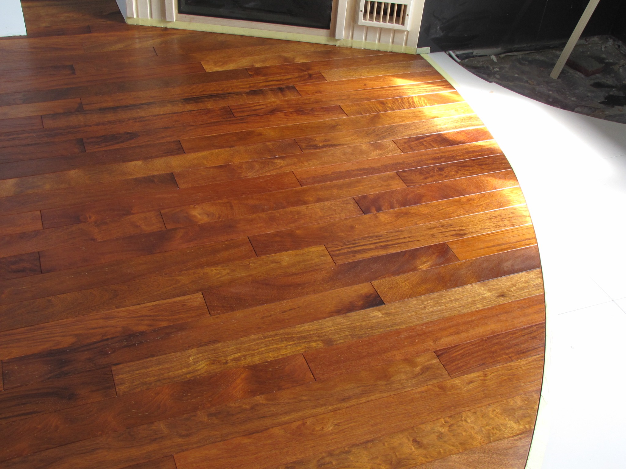 Wycyklinowana i polakierowana podłoga parkietowa z widocznym fragmentem kominka i zabezpieczeniem folią malarską.