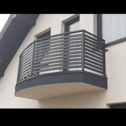 KAM-Weld KAMIL DOROSZ - Nowoczesna balustrada balkonowa z poziomych, szarych profili, zamontowana na zaokrąglonym balkonie w jasnym budynku.