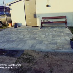 Zakład remontu dróg i ulic Marcin Skrzypa - Szara kostka brukowa ułożona na posesji, obok domu z ławeczką i kotami, widok z poziomu gruntu.