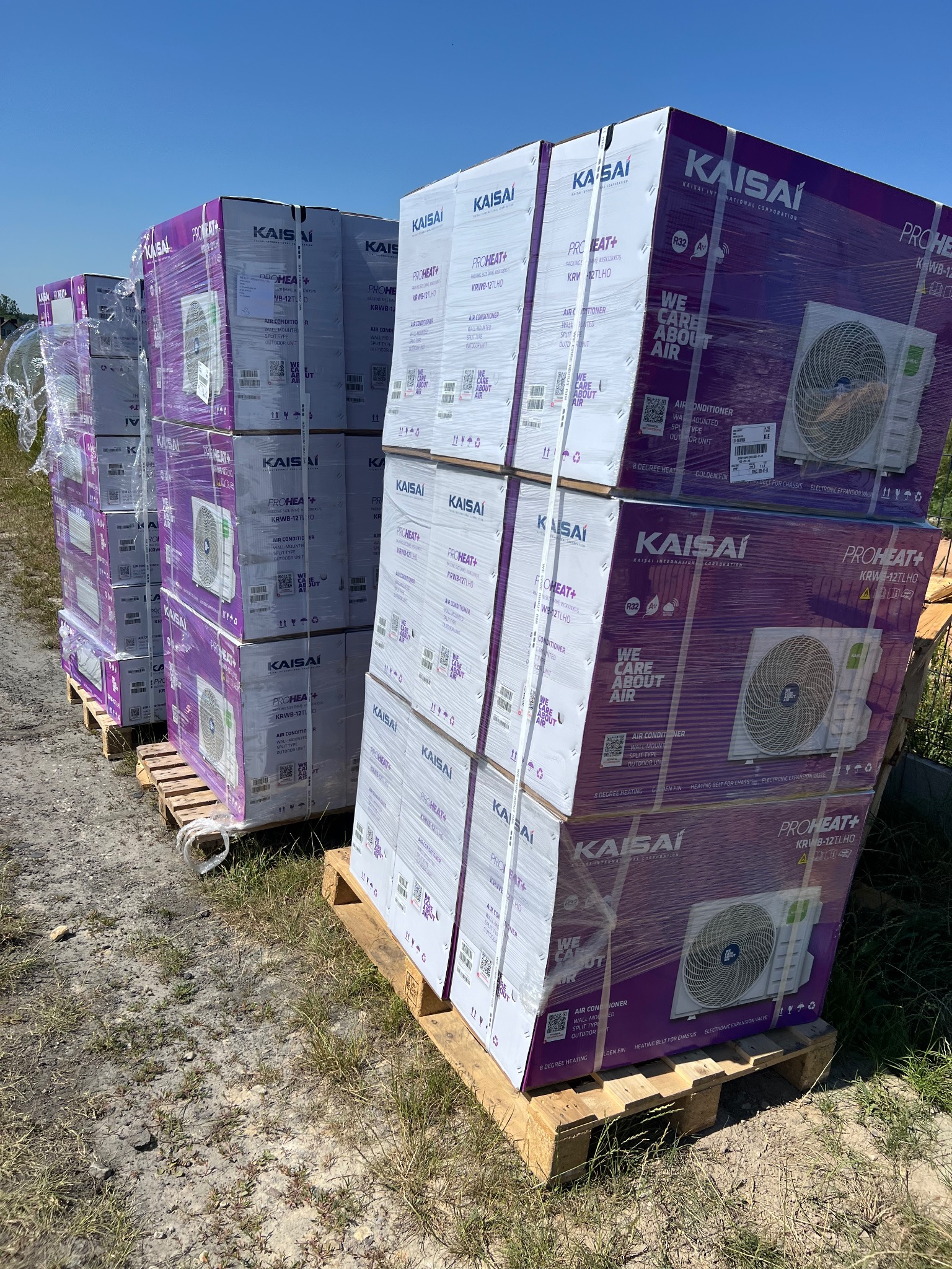 Pakiety klimatyzacji Kaisai na paletach, gotowe do transportu w Kielcach. Widoczne modele Pro Heat+ w folii ochronnej, składowane na zewnątrz.