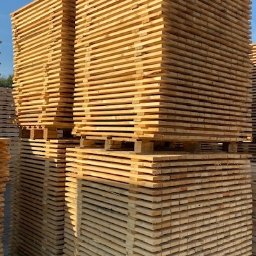 Tartak Amesko Spółka Jawna Monika Skóra-Szydłowska,Artur Szydłowski - Stosy świeżo przetartego drewna ułożone na paletach, widoczne słoje i jasna barwa surowca.