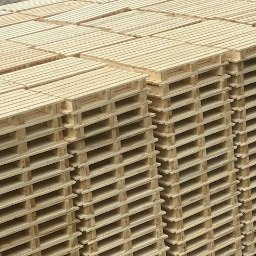 Tartak Amesko Spółka Jawna Monika Skóra-Szydłowska,Artur Szydłowski - Stosy nowych, jasnych palet drewnianych ułożonych równo na zewnątrz, widoczne szare podłoże w tle.