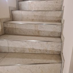 Usługi budowlane płytki - Schody wyłożone płytkami imitującymi marmur, z metalowymi listwami na krawędziach stopni, widok z góry.