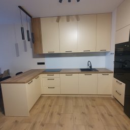 Twoje M. Meble na wymiar - Jasna kuchnia na wymiar z drewnianym blatem i czarną armaturą, widziana w Łopienniku Dolnym-Kolonii, oświetlona nowoczesnymi lampami wiszącymi.
