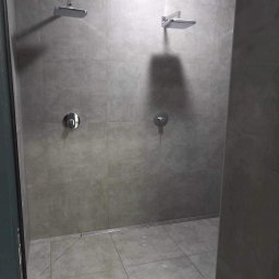 Sawik - Wykończona łazienka z dwoma prysznicami typu deszczownica, szare płytki na ścianach i podłodze, odpływ liniowy w podłodze, widok z boku.