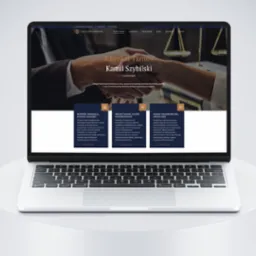 Laptop prezentuje stronę internetową kancelarii adwokackiej z Tarnowa, z nagłówkiem 'Adwokat Tarnów Kamil Szybilski' i zdjęciem uścisku dłoni na tle wag sprawiedliwości.