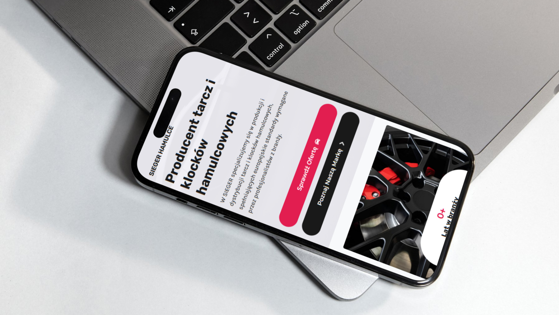 Smartfon wyświetlający stronę internetową producenta tarcz i klocków hamulcowych Sieger Hamulce, leżący na laptopie.