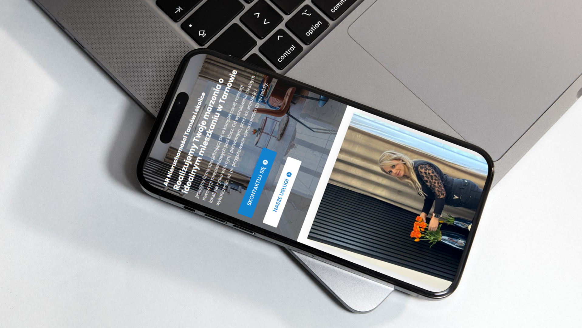 Smartfon wyświetlający stronę internetową agencji nieruchomości na tle laptopa, widoczne przyciski 'Skontaktuj się' i 'Nasze usługi'.