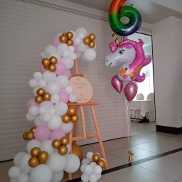 Odlotove&Balonove - Dekoracja balonowa na Chrzest Święty Emilii: biało-różowo-złota girlanda balonowa oparta o drewniany stojak z napisem, obok balony foliowe w kształcie jednorożca i cyfry 6 w kolorach tęczy.