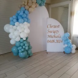 Dekoracja balonowa z białym panelem z napisem 'Chrzest Święty Michała 04.08.2024' na drewnianej podłodze.