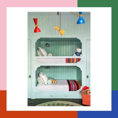 Niebiesko-zielone łóżko piętrowe w zabudowie z trzema kolorowymi lampami wiszącymi, poduszki dekoracyjne, pluszowy miś na górnym łóżku i kosz z zabawkami na podłodze.