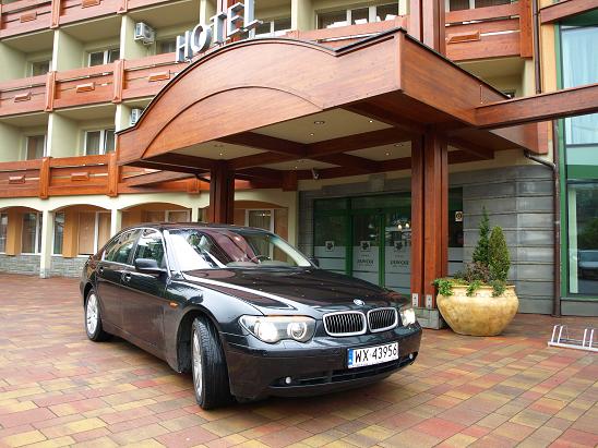 Czarna limuzyna BMW serii 7 parkuje przed wejściem do hotelu, widoczny numer rejestracyjny WX 43956.