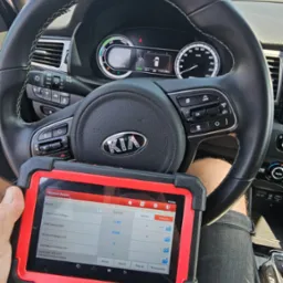 Diagnostyka komputerowa pojazdu marki Kia Niro, odczyt danych z tabletu diagnostycznego na tle kierownicy i deski rozdzielczej.