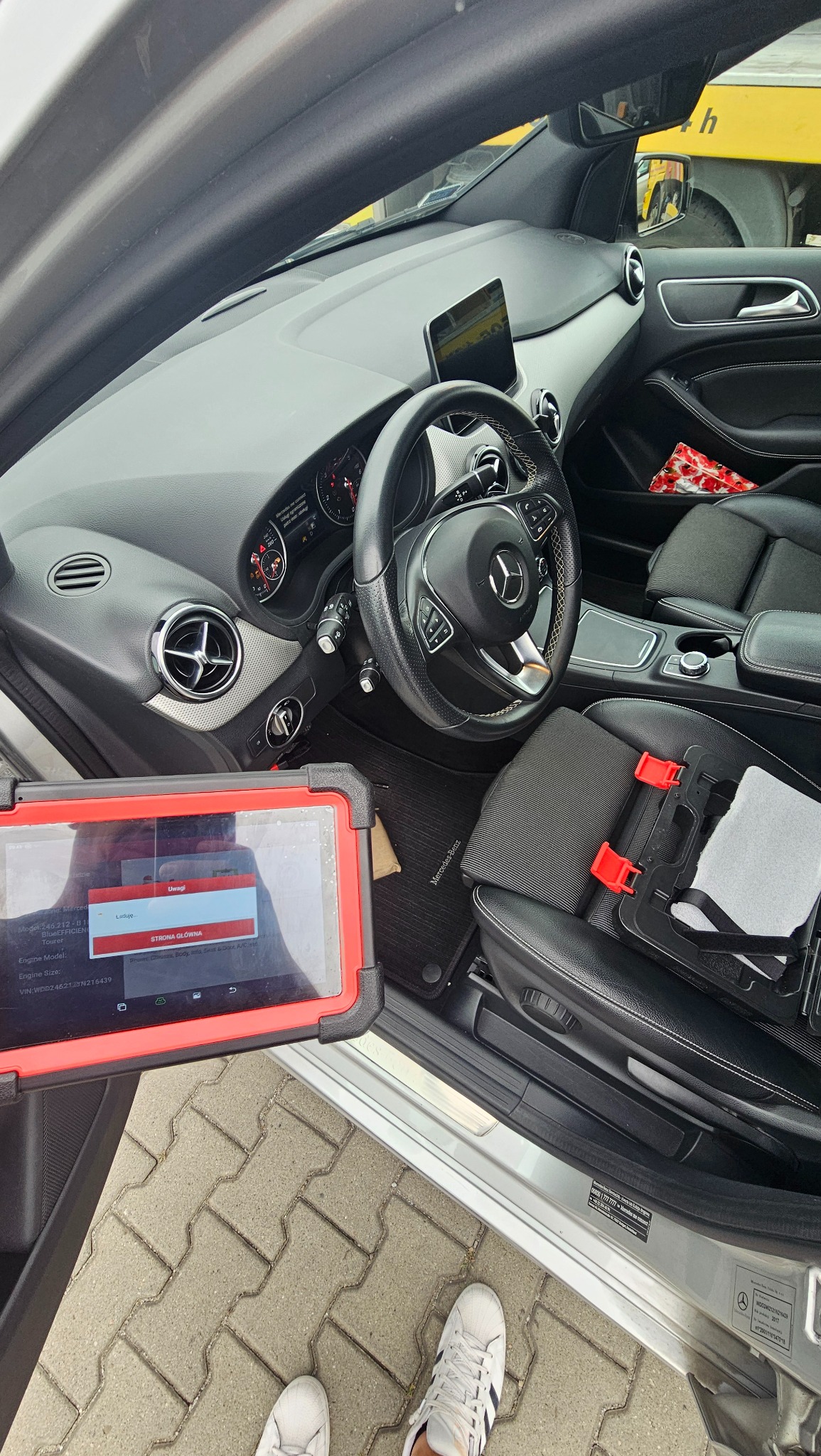 Wnętrze samochodu marki Mercedes z podłączonym tabletem diagnostycznym z widocznym interfejsem oprogramowania diagnostycznego.