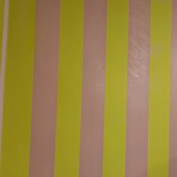 Team-Lewy - Pomalowana ściana w pionowe pasy w odcieniach żółci i pudrowego różu, widoczne niebieskie taśmy malarskie przy suficie.