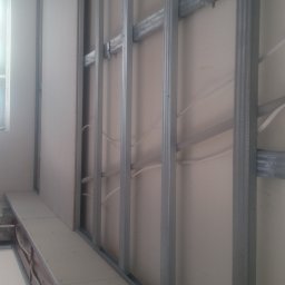 DOM SERWIS Krzysztof Chodorowski - Montaż płyty karton gips na metalowej konstrukcji, widoczne przewody elektryczne w ścianie, częściowo zamontowane płyty.