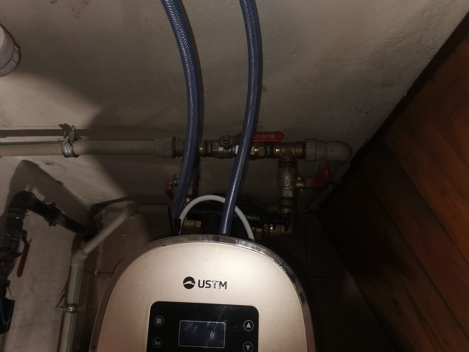 Zamontowany piec gazowy USTM z podłączonymi niebieskimi przewodami w kotłowni, widoczne zawory i rury instalacji.