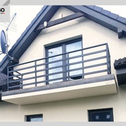 WBO Oskar Winowiecki - Nowoczesna, grafitowa balustrada balkonowa z poziomych profili, zamontowana na jasnym budynku z ciemną stolarką okienną i dachem. Widok z dołu, antena satelitarna w tle.