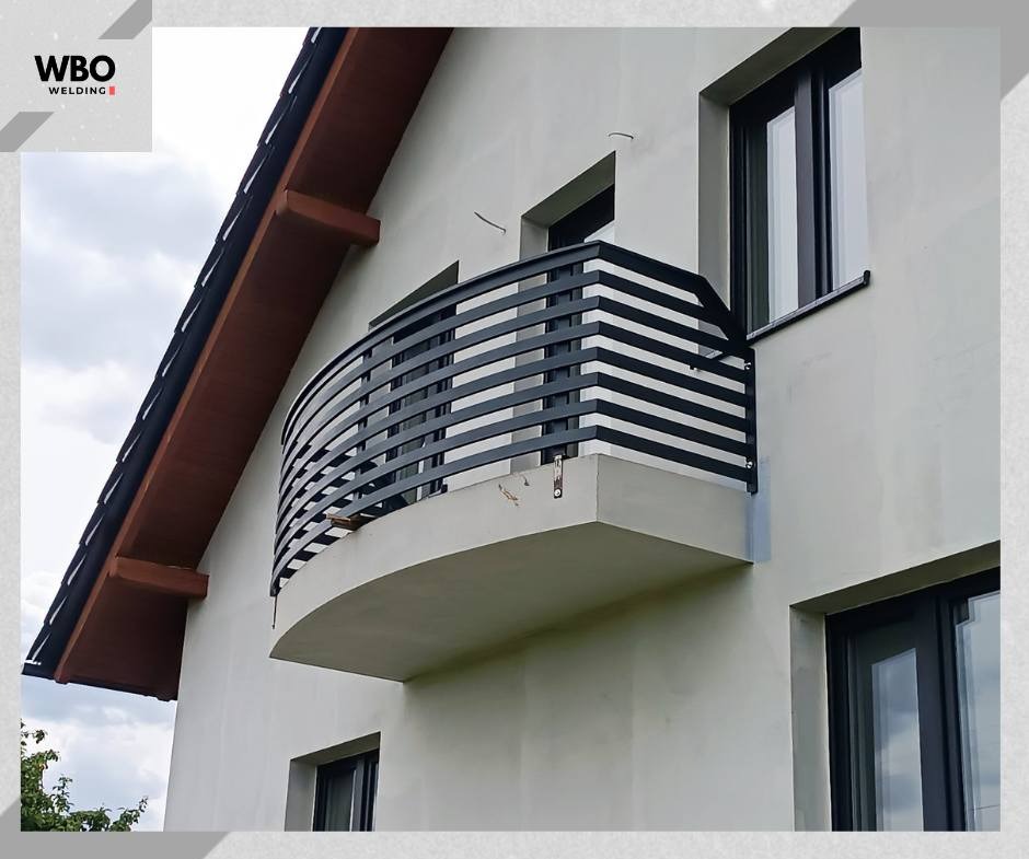 Elegancka, czarna, pozioma balustrada balkonowa z metalu, zamontowana na zaokrąglonym balkonie w nowoczesnym domu. Ujęcie z dołu, podkreślające geometrię konstrukcji.