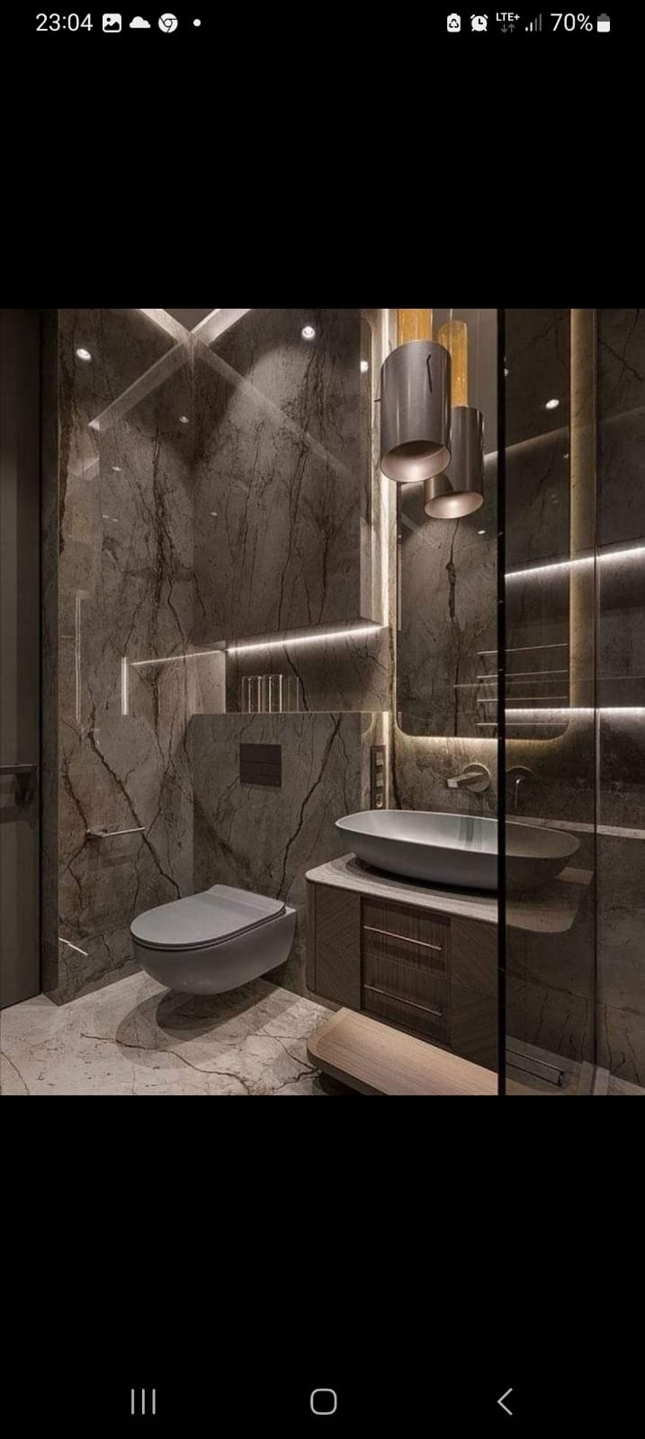 Elegancka łazienka z marmurowymi ścianami, podwieszaną toaletą, owalną umywalką nablatową, podświetlanym lustrem i designerskimi lampami wiszącymi.