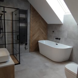 MAPKIM remonty - Nowoczesna łazienka na poddaszu z oknem dachowym, szarą płytką podłogową i ścienną, białą wolnostojącą wanną, czarną kabiną prysznicową typu walk-in oraz grzejnikiem drabinkowym w tym samym kolorze...