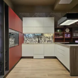 Nowoczesna kuchnia w odcieniach czerwieni, bieli i drewna, z marmurowym backsplashiem i minimalistycznym oświetleniem podszafkowym.