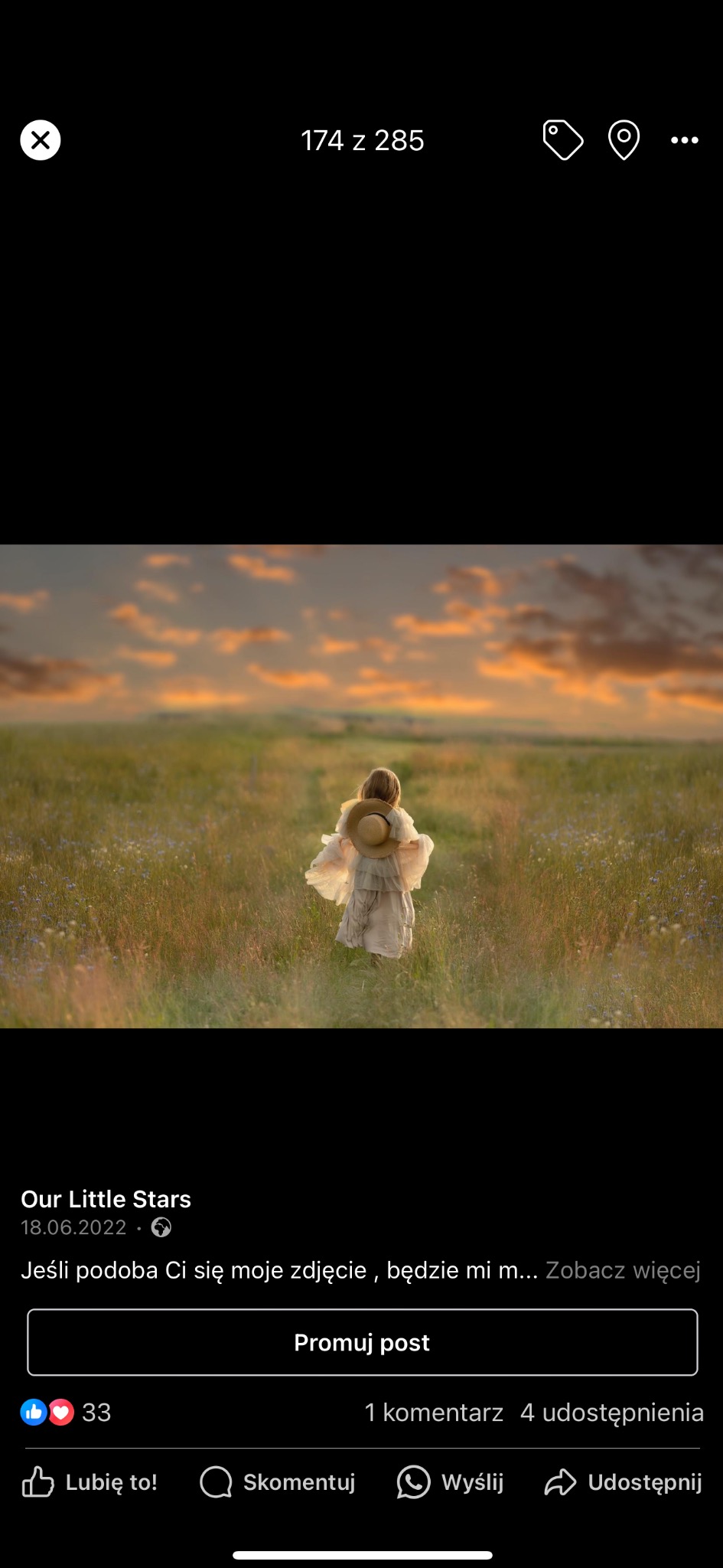 Dziewczynka w jasnej sukience i słomkowym kapeluszu idzie przez łąkę w kierunku zachodzącego słońca, widok z tyłu.