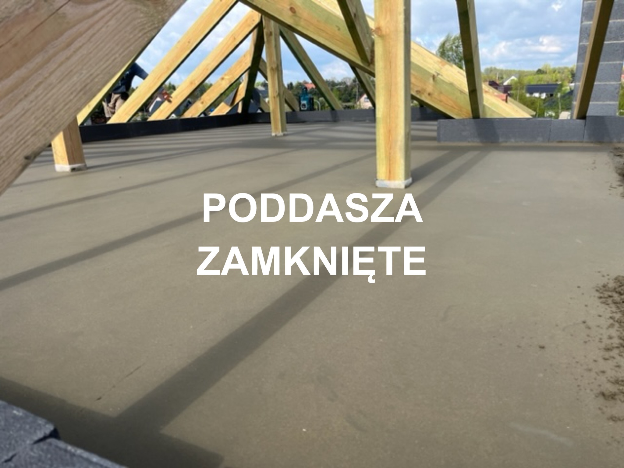 Świeżo wylana, gładka posadzka jastrychowa na poddaszu z widoczną drewnianą konstrukcją dachu i bloczkami betonowymi w tle.