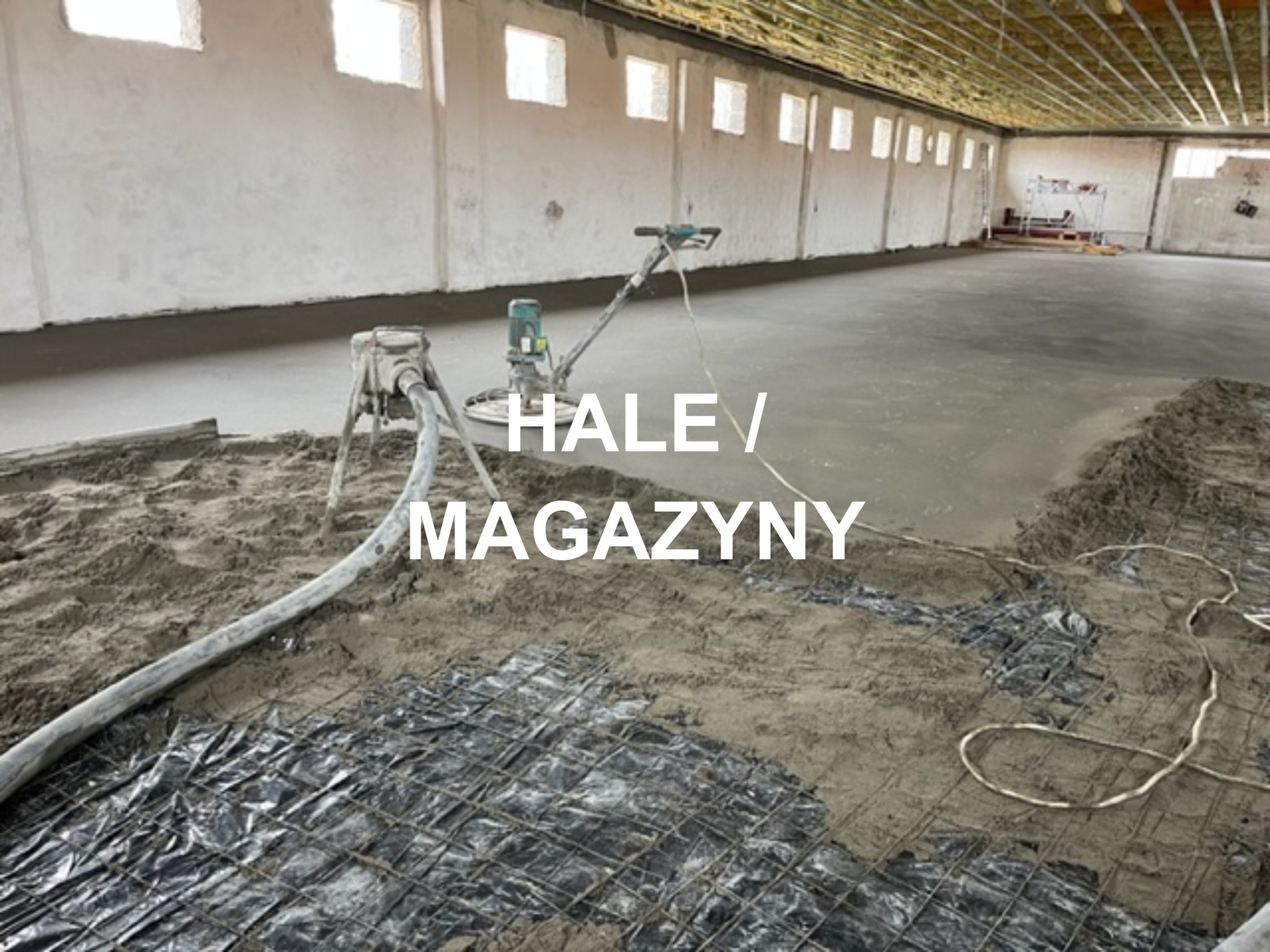 Wnętrze hali magazynowej w trakcie wylewania posadzki: widoczna siatka zbrojeniowa, pompa do betonu, zacieraczka oraz świeżo wylana, częściowo wygładzona powierzchnia.