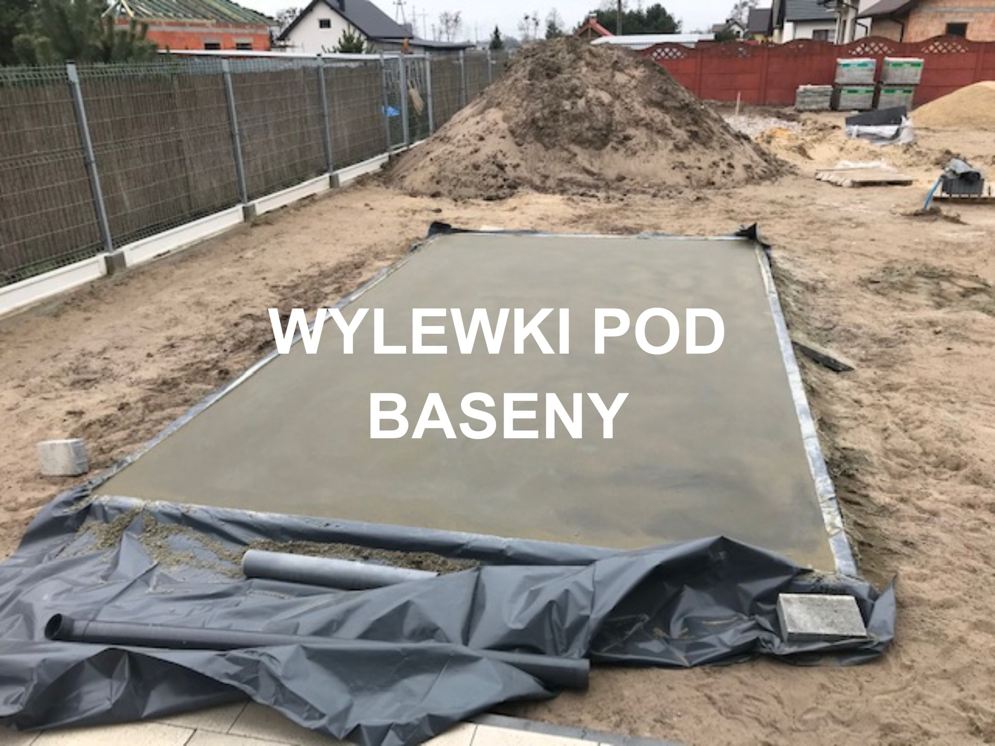 Wylewka betonowa przygotowana pod budowę basenu, zabezpieczona folią, z widocznymi rurami odpływowymi i stertą piasku w tle.
