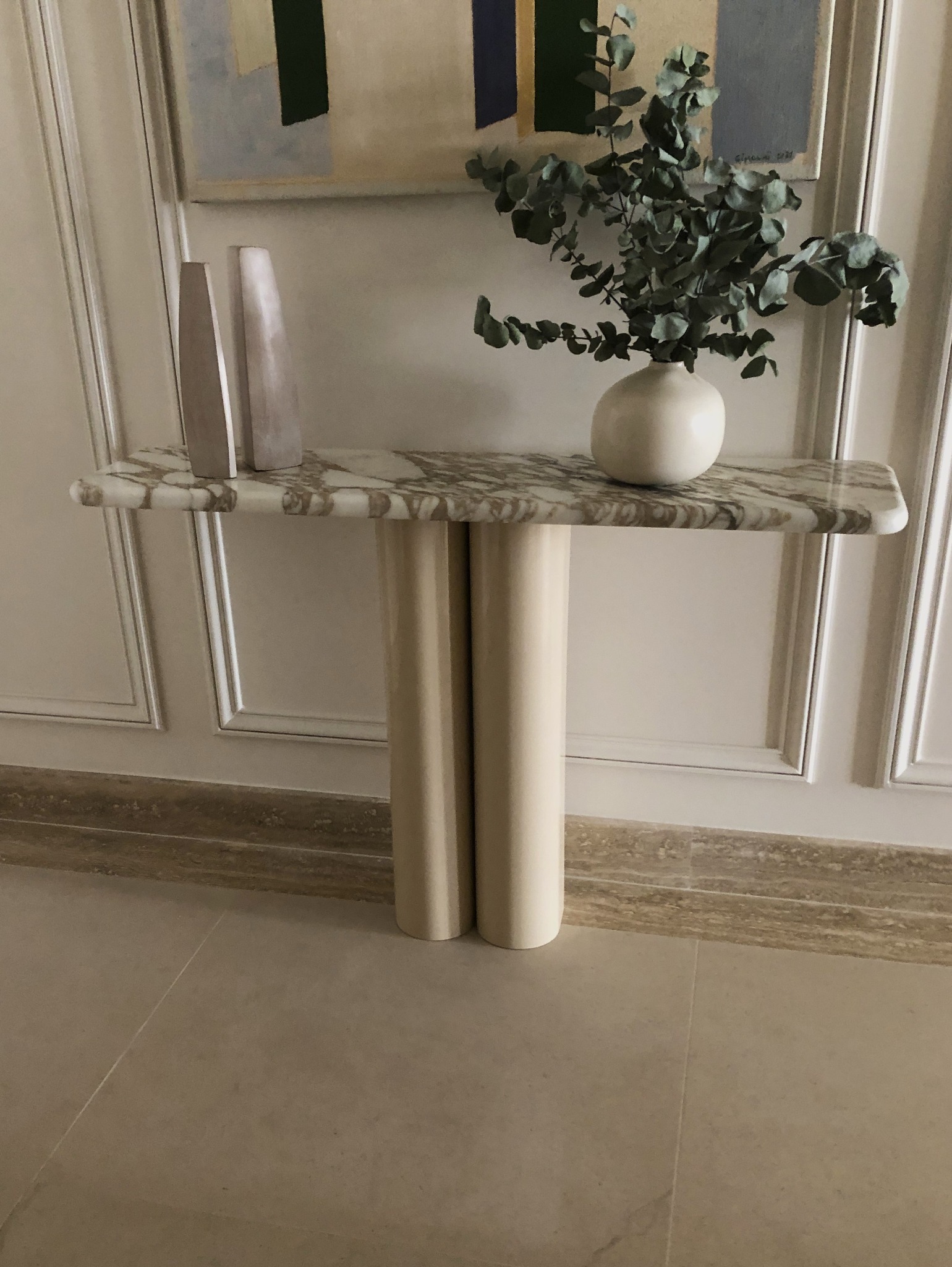 Konsola z kamiennym blatem oraz metalowymi nogami lakierowanymi w połysk.