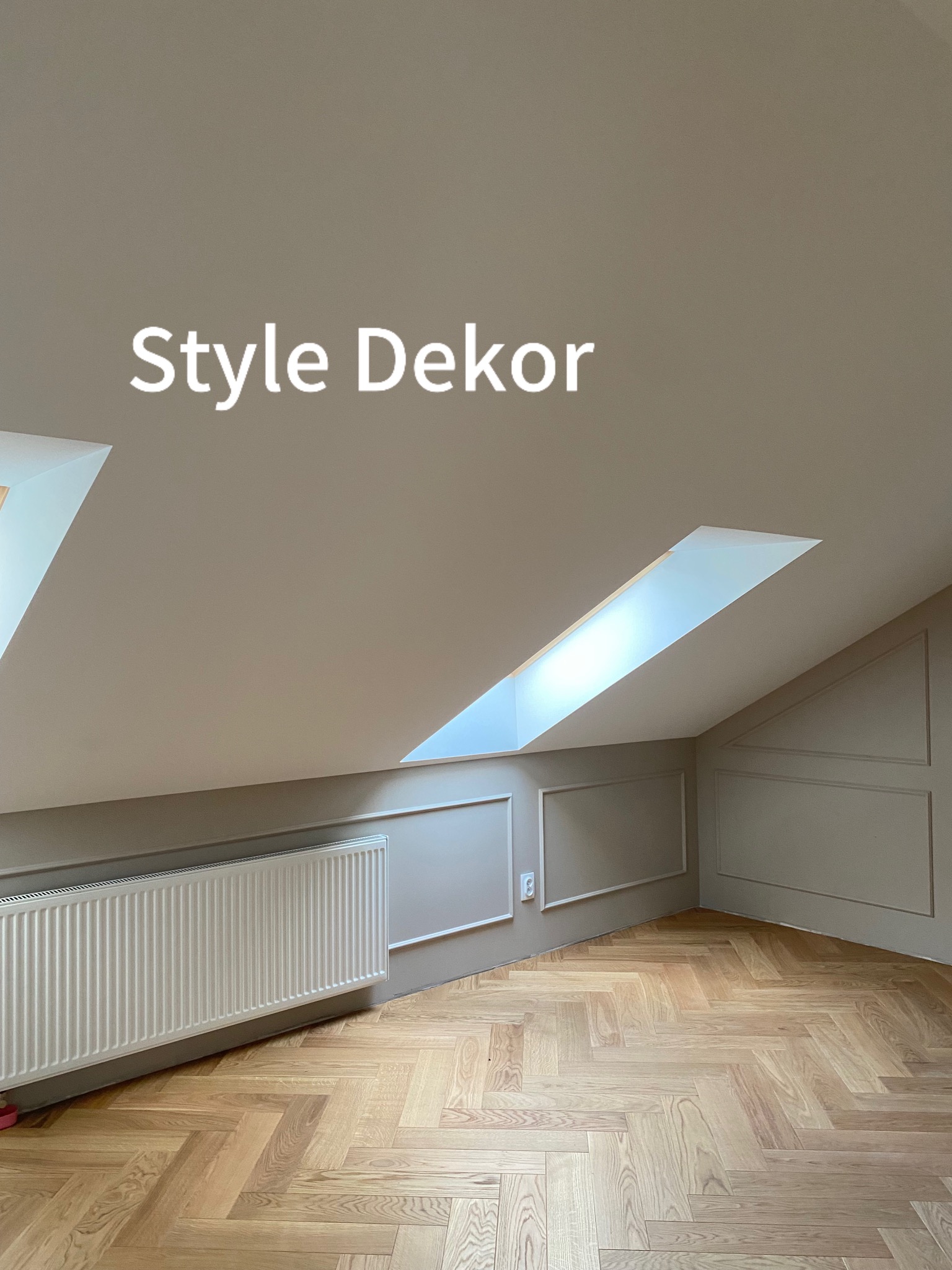 Poddasze po remoncie: Ściany w odcieniach szarości z dekoracyjnymi listwami, parkiet ułożony w jodełkę, biały grzejnik, okno dachowe w skosie. Na ścianie widoczny napis 'Style Dekor'.