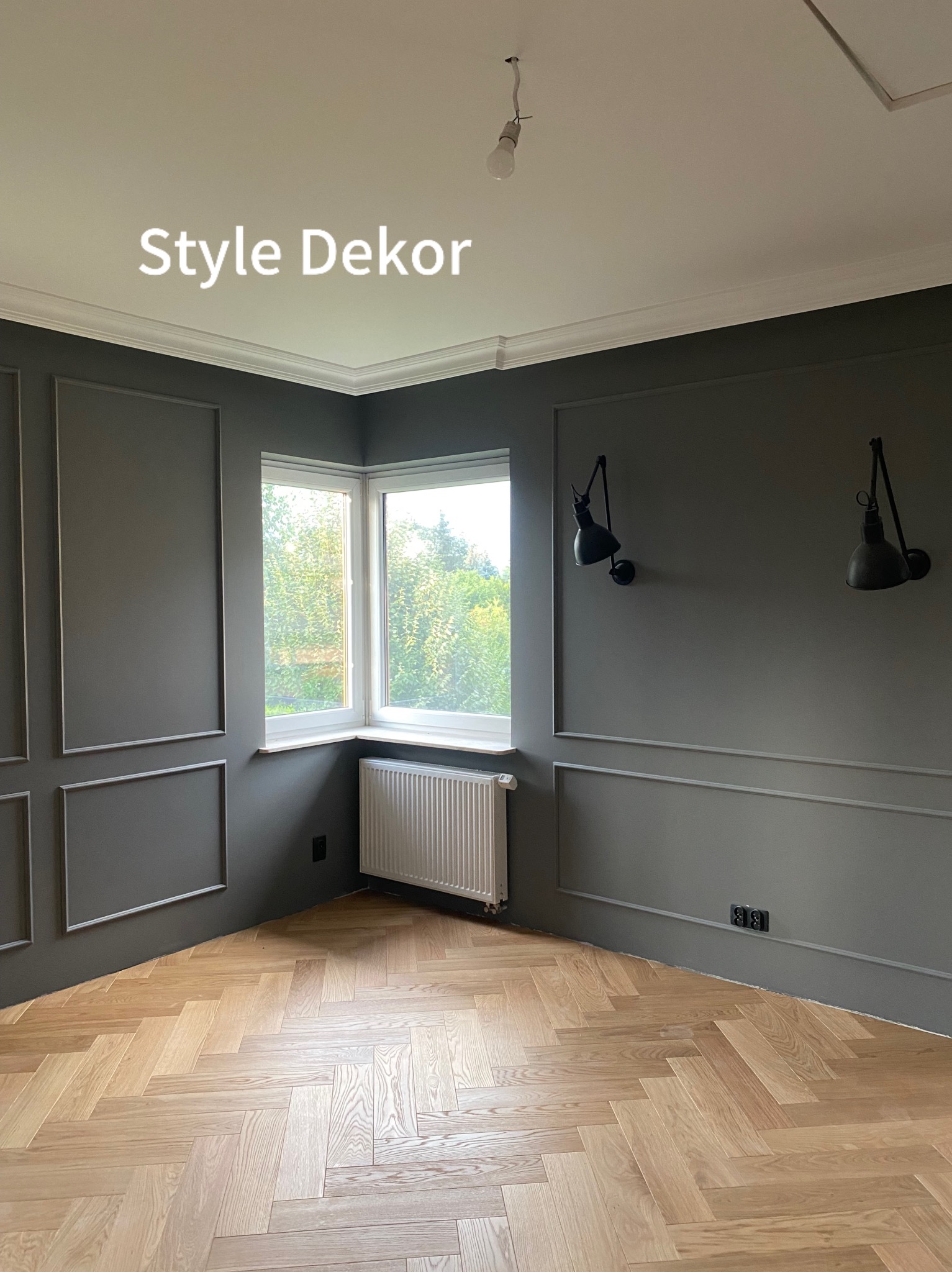 Eleganckie wnętrze w odcieniach szarości z parkietem w jodełkę, dekoracyjnymi listwami ściennymi i czarnymi lampami ściennymi.