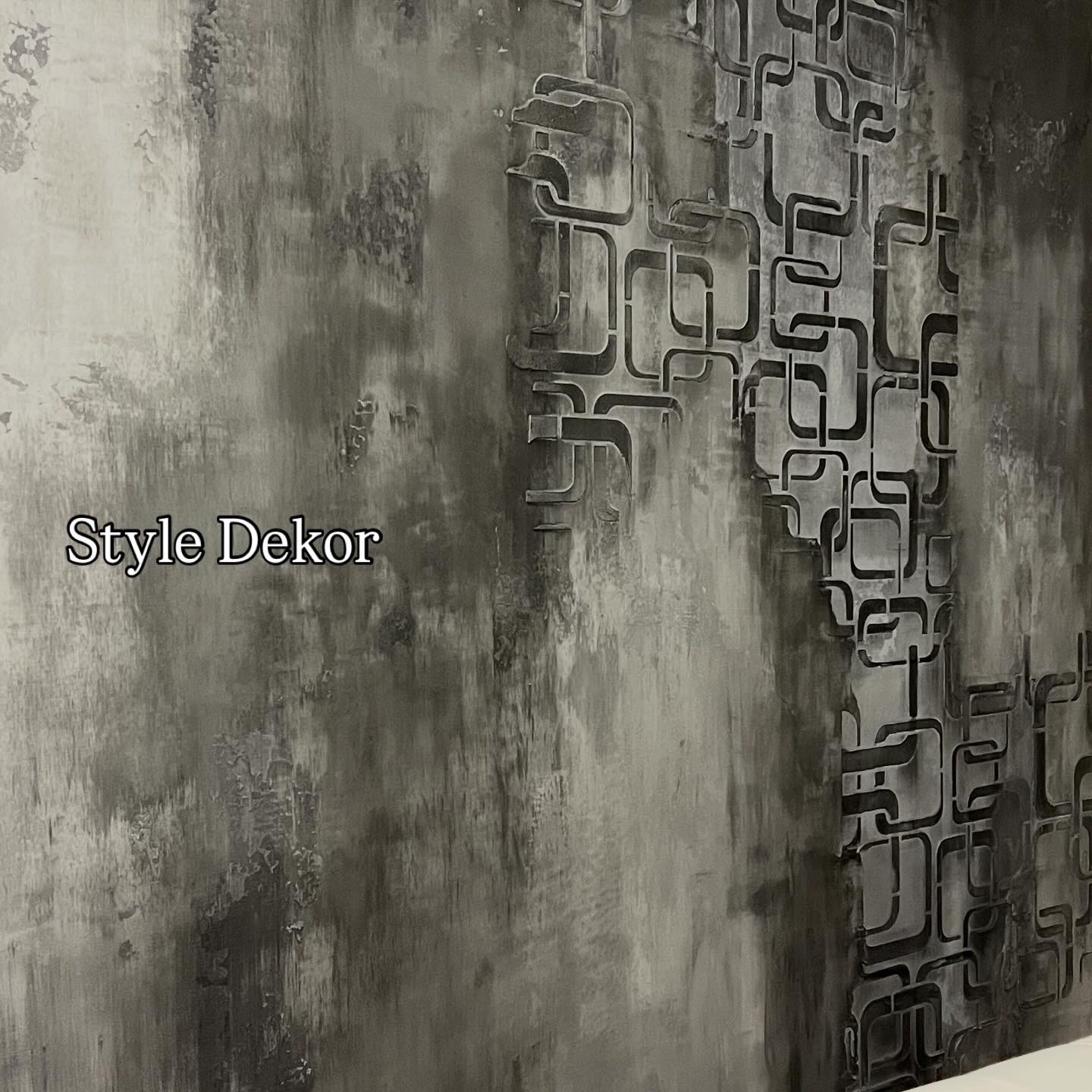 Dekoracyjna ściana w odcieniach szarości z geometrycznym wzorem, wykonana techniką strukturalną. Widoczna faktura i gra światłocieni.