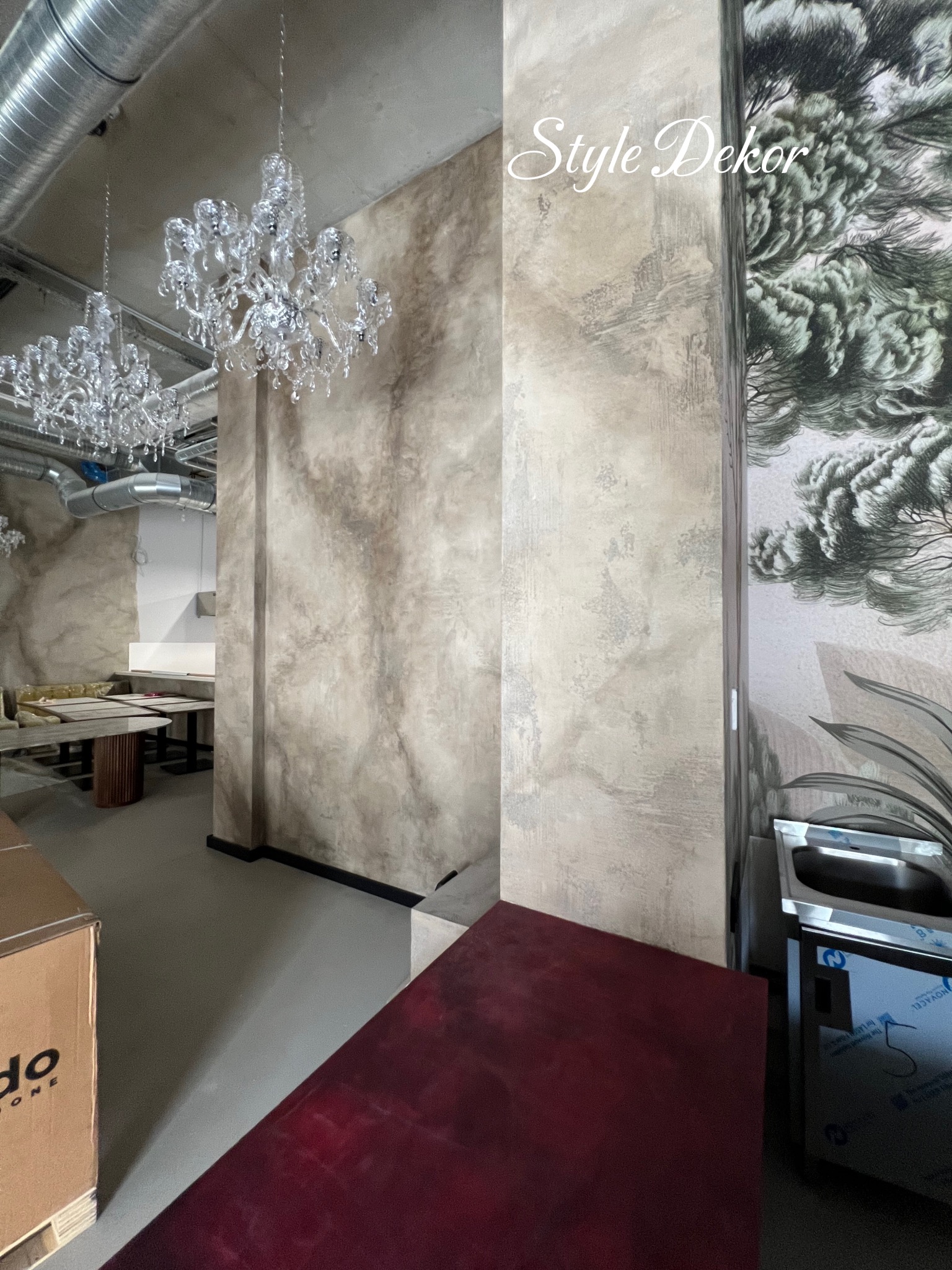 Wykończenie ścian w restauracji z dekoracyjną fakturą i motywem drzewa. Widoczne kryształowe żyrandole i elementy wyposażenia. Styl dekoracyjny.