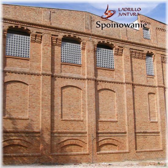 Elewacja budynku z cegły klinkierowej z dekoracyjnymi elementami architektonicznymi i oknami z luksferami.