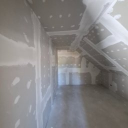 Usługi remontowo wykończeniowe marcin pępek - Poddasze po szpachlowaniu, widoczne płyty karton-gips z nałożoną warstwą szpachli. Skosy dachu i sufitu wykończone, przygotowane do dalszych prac wykończeniowych.